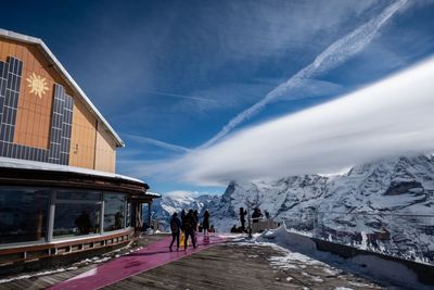 People on snowcapped mountain against sky