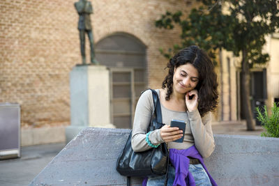 Woman smiling while talking on the phone outdoors.