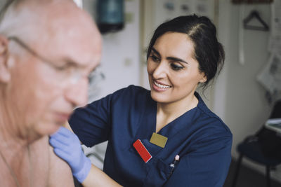 Smiling female nurse doing medical exam of senior patient at hospital