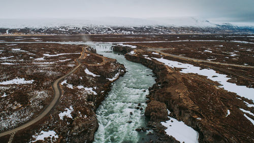 Aerial view of snow covered land against sky