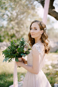 Portrait of young woman standing against plants