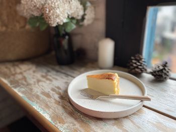 Cheesecake on the plate with flowers in the background