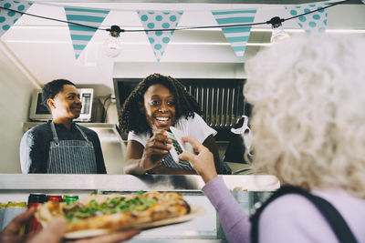 Smiling owner talking to customer about payment while standing in food truck