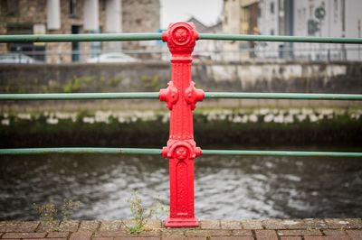 Close-up of red railing by river