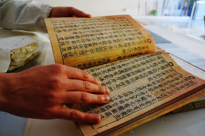 Close-up of hand holding book with text