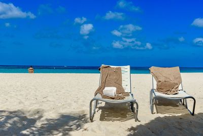 Deck chairs on beach against blue sky