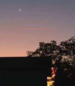 Low angle view of silhouette tree and building against sky during sunset