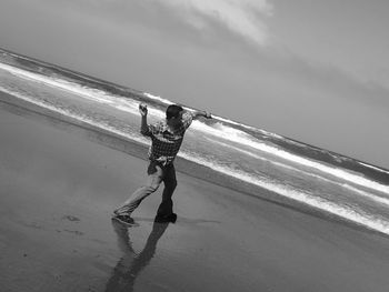 Man with umbrella on beach against sky
