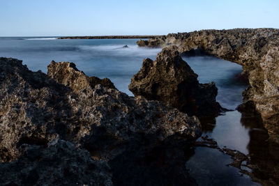 Rock formations on sea shore against sky