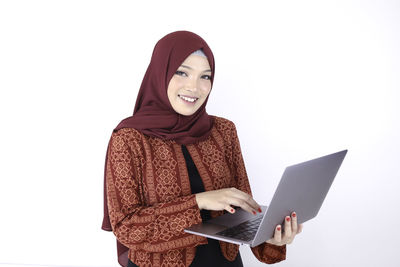 Portrait of smiling young woman holding smart phone