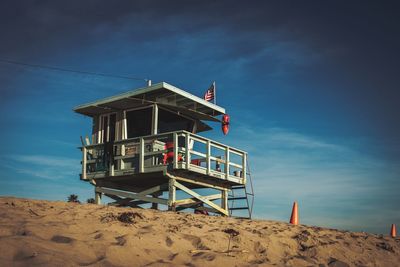 Lifeguard hut on beach against blue sky