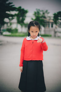 Portrait of cute girl pointing while standing on road