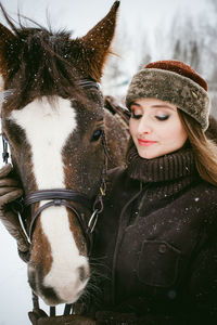 Close-up of beautiful woman with horse on field during snowfall