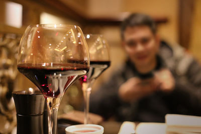 Close-up of wineglasses against smiling man in restaurant