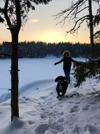 Woman playing with dog on field against sky during winter