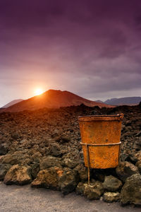 Sunset in timanfaya with rusty metal basket in the foreground