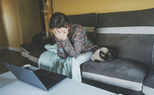 Frustrated woman sitting on sofa at home