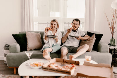 Young woman using phone while sitting on sofa at home