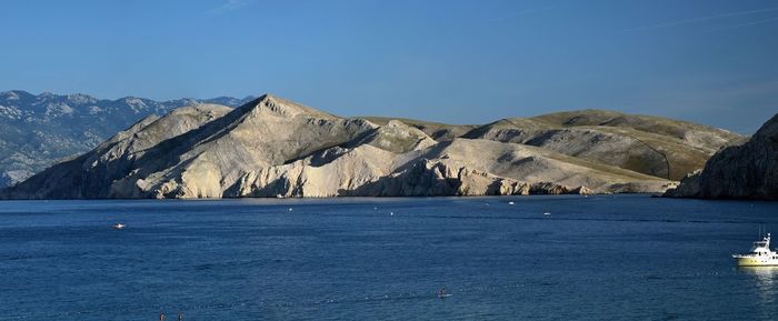 Scenic view of sea and mountains against blue sky