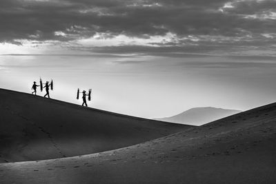 People standing on sand against sky