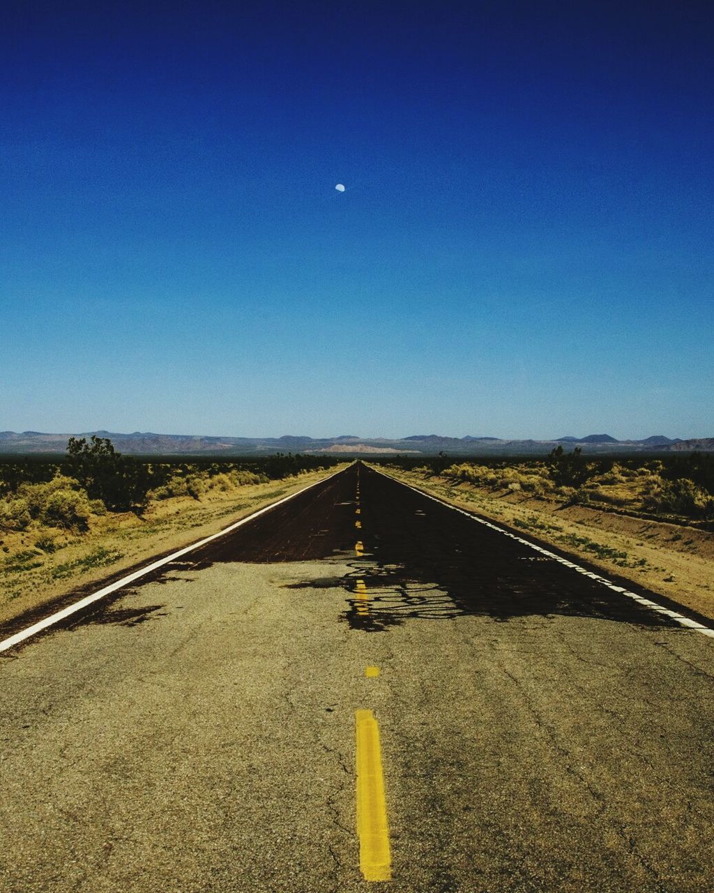 clear sky, copy space, blue, the way forward, road, transportation, diminishing perspective, road marking, landscape, vanishing point, yellow, tranquil scene, asphalt, tranquility, outdoors, nature, direction, no people, country road, surface level