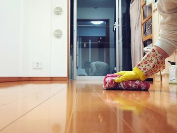 Low section of woman on wooden floor at home