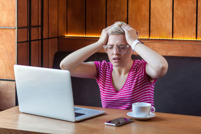 Young woman using mobile phone while sitting on table