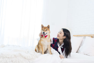 Woman with dog sitting on bed