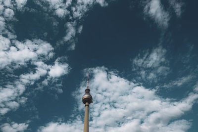 Low angle view of communications tower against cloudy sky