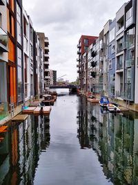 Canal amidst buildings in city against sky