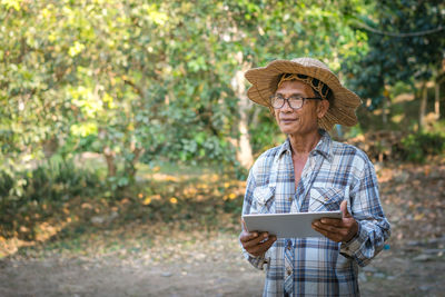 Portrait of man holding camera while standing outdoors