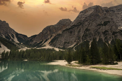 Scenic view of lake and mountains against sky during sunset