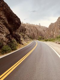 Empty road by mountain against sky