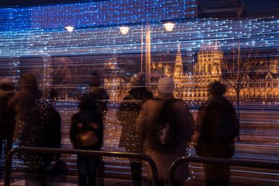 Group of people in front of illuminated city at night