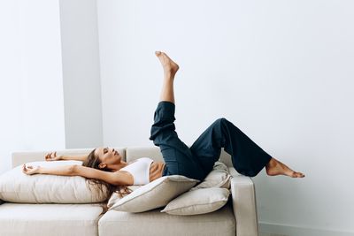 Low section of woman sitting on sofa at home