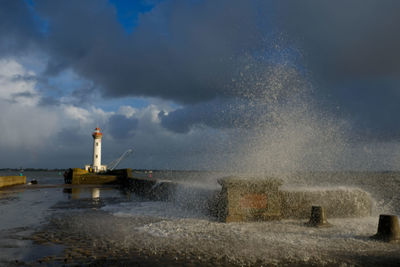 Waves splashing on shore against sky