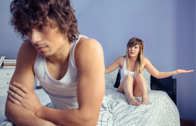 Young couple sitting on bed at home