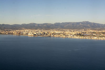 Aerial view of townscape by sea against sky