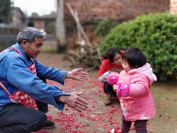 Grandfather with granddaughter playing outdoors