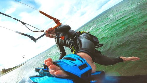 Low section of man skateboarding on sea against sky