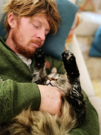 High angle view of man with cat sleeping on sofa at home