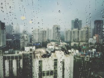 City seen through wet glass window during rainy season