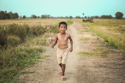 Portrait of happy boy walking on field
