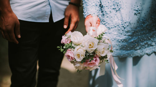 Midsection of man holding flower bouquet