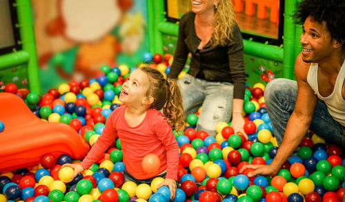 Happy family playing with multi colored balls in pool