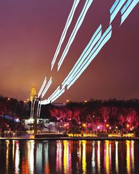 Illuminated bridge over river against sky at night