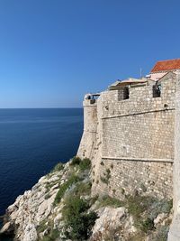 Building by sea against clear blue sky