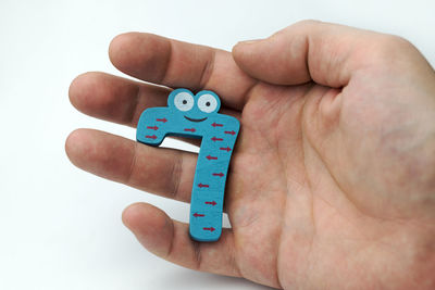 Close-up of hand holding toy against white background