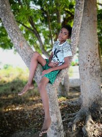 Full length of boy sitting on tree trunk