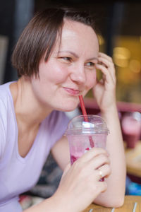 Young woman looking away while having drink at cafe